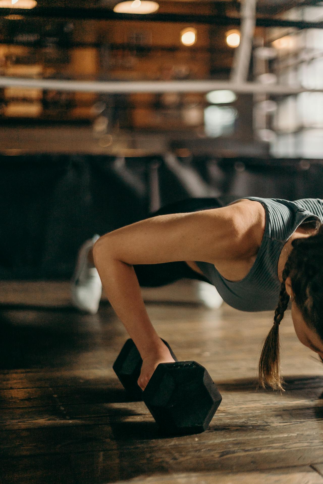 A lady doing push-up with a dumbbell in her hand.