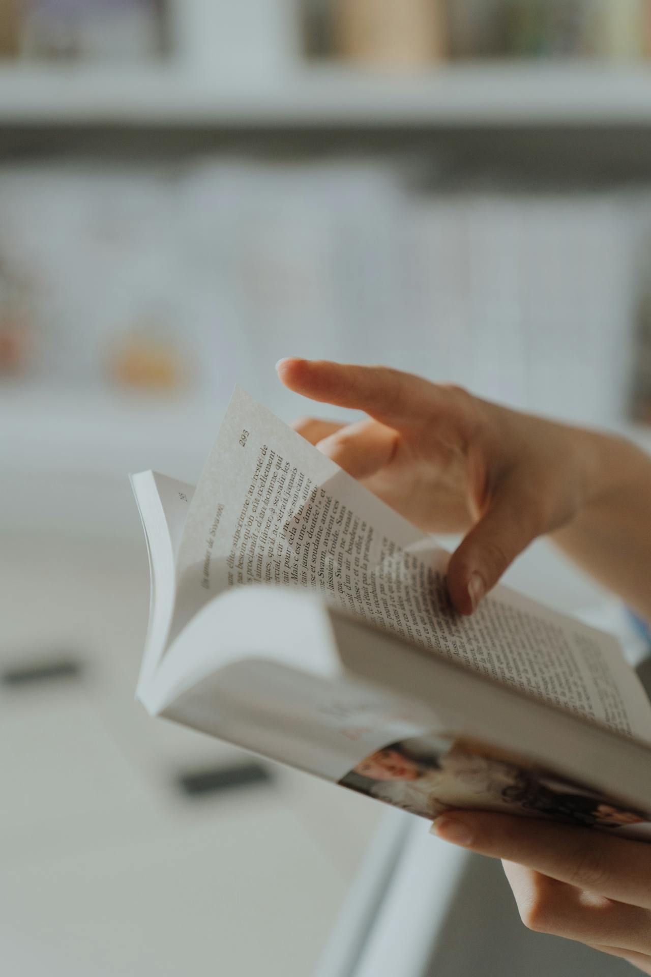 An adult reading a book by flipping a page of it.