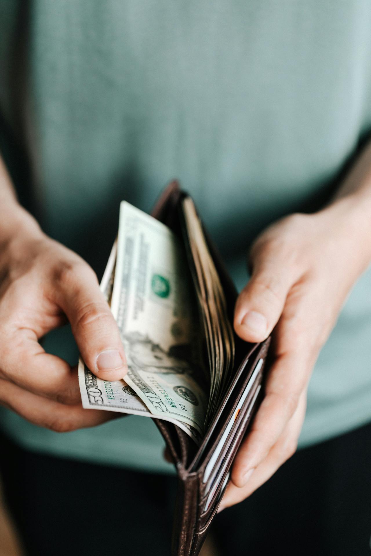 A man holding a wallet and taking some banknotes out of it.