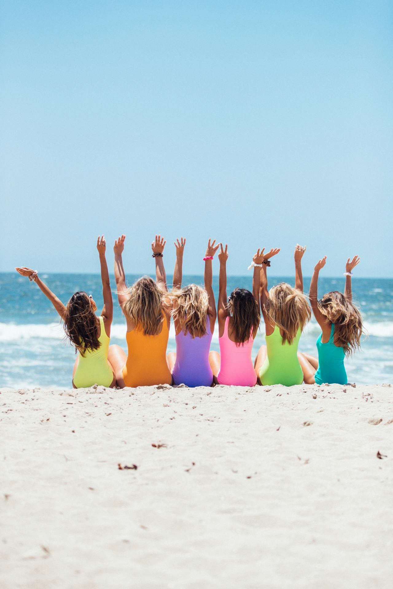 Six children sitting together on a beach showing friendship.