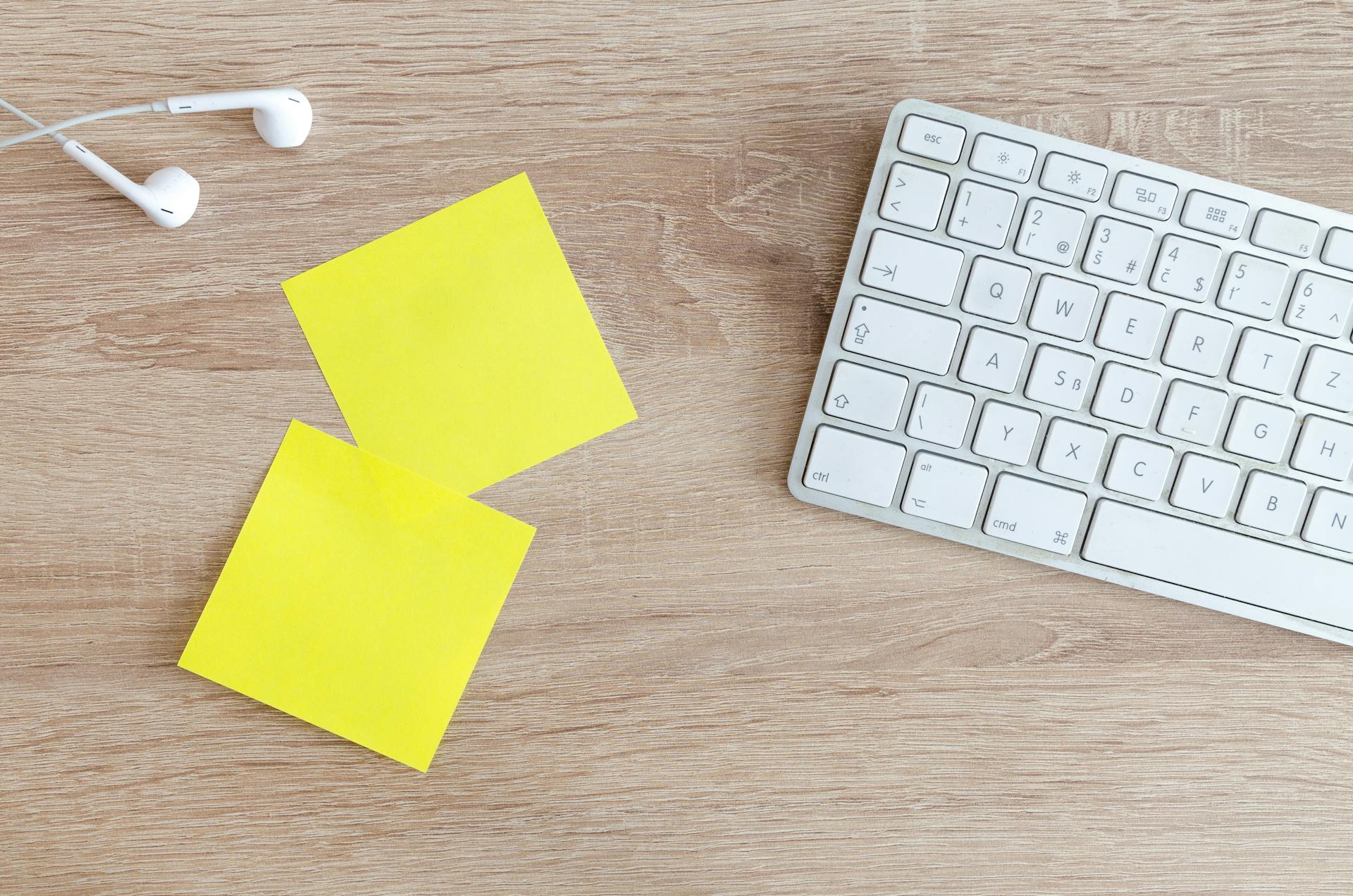 A keyboard, two memo papers and a headphone placed on a desk.